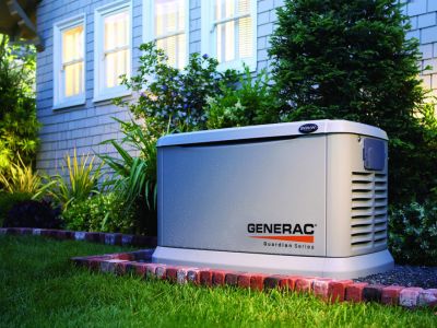 Standby generator by Generac in a residential yard, highlighting automatic power backup solution during outages, surrounded by greenery and illuminated at night.